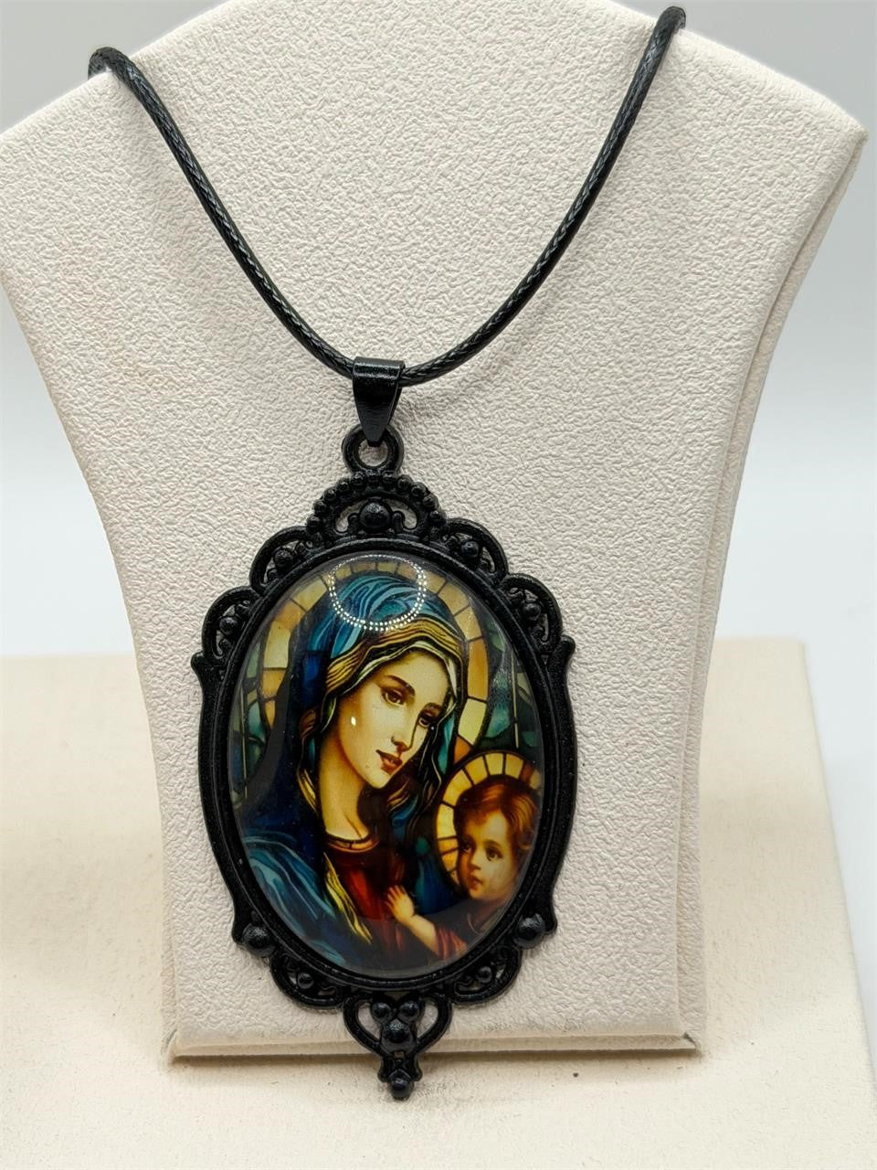Virgin Mary pendant necklace in black with a rope chain, featuring a detailed religious charm for women.