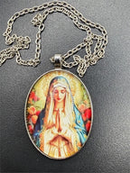 Virgin Mary enameled pendant necklace with detailed religious iconography, featuring a silver chain and vibrant blue and gold accents.