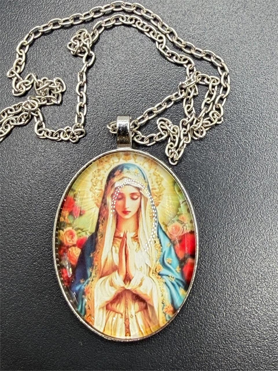 Virgin Mary enameled pendant necklace with detailed religious iconography, featuring a silver chain and vibrant blue and gold accents.