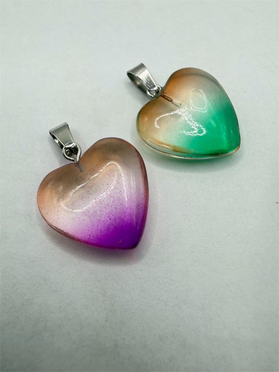 Two heart-shaped glass pendants with silver chains from Republic Mercantile, close-up showing clear glass and silver details.