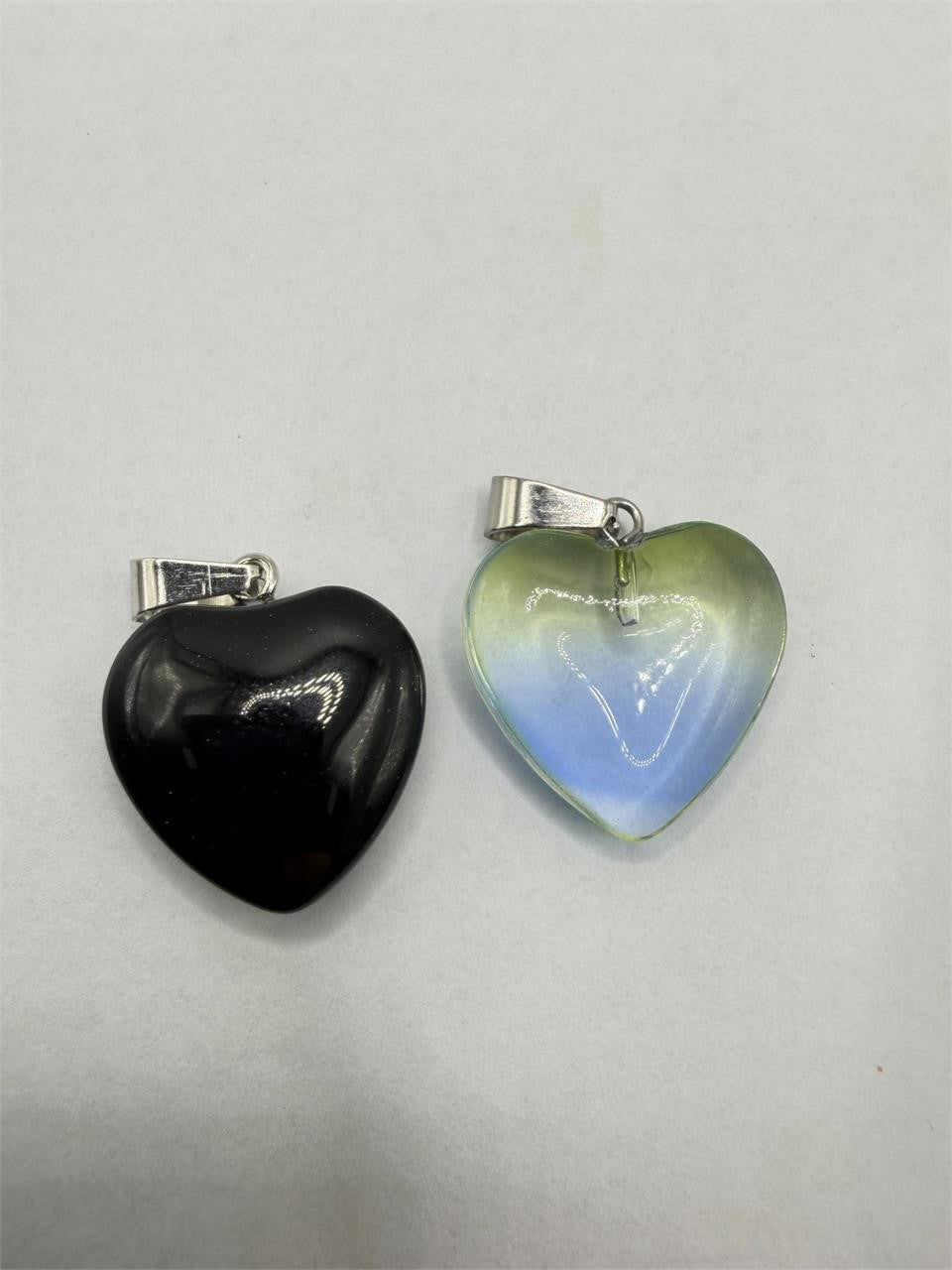 Two heart-shaped glass pendants with silver chains from Republic Mercantile, close-up of detailed jewelry accessories.