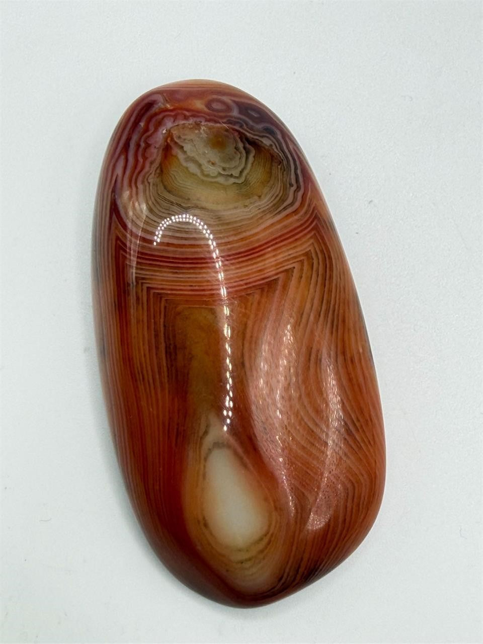 Polished banded agate loose gemstone cabochon from Republic Mercantile, showcasing colorful natural stone with smooth, rounded surface.