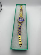 Women's gemstone watch in blue on gold band, Republic Mercantile jewelry with elegant design and sparkling blue gemstone accents.
