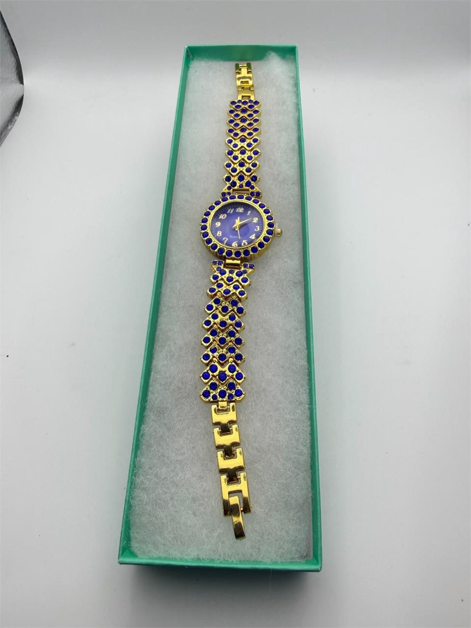 Women's gemstone watch in blue on gold band, Republic Mercantile jewelry with elegant design and sparkling blue gemstone accents.