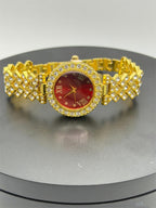 Women's gemstone watch with a red dial on a gold bracelet by Republic Mercantile, showcasing elegant jewelry design.