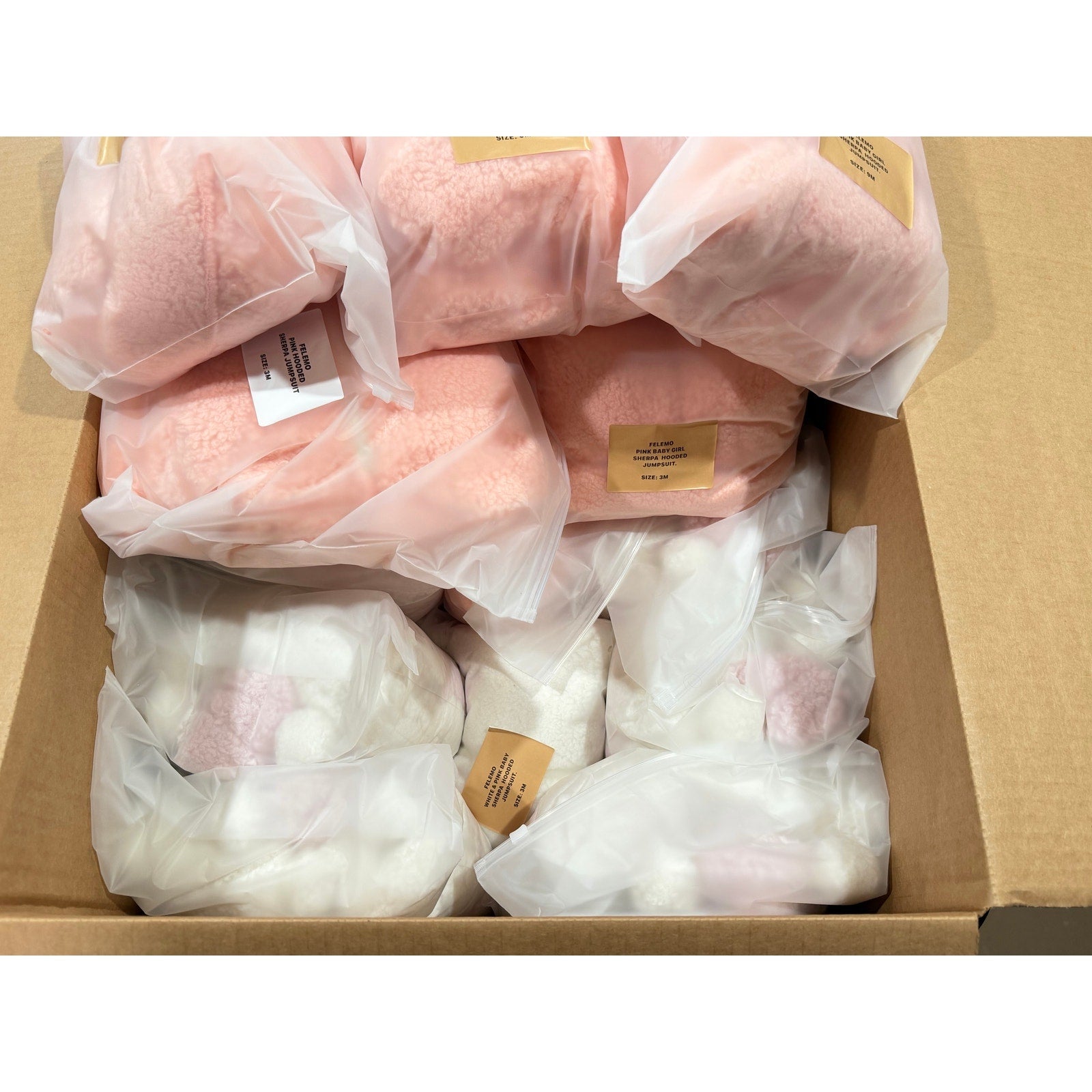 Set of 21 pink and white infant jumpsuits from Republic Mercantile, perfect for resellers, displayed in a wholesale box.
