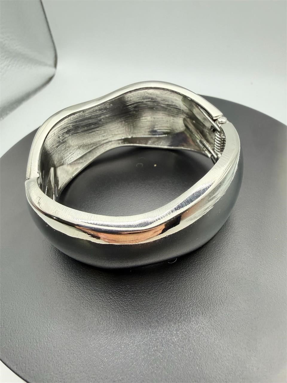 Large silver-tone spring action bangle bracelet with a smooth, polished finish and open design, by Republic Mercantile.