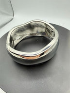 Large silver-tone spring action bangle bracelet with a smooth, polished finish and open design, by Republic Mercantile.