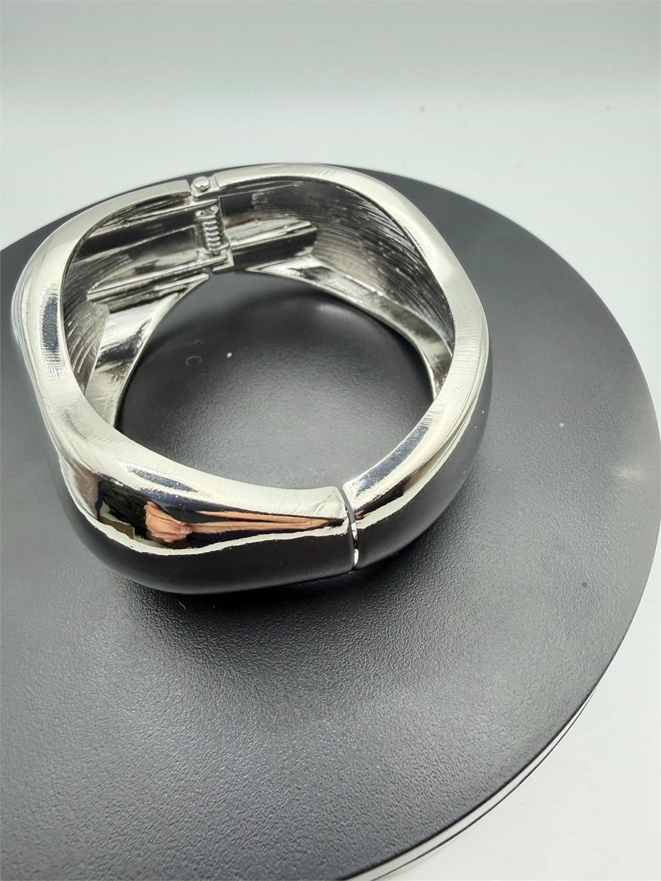Large silver tone spring action bangle bracelet with smooth, sleek design, showcasing a sturdy, fashionable accessory.