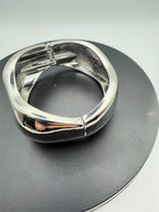 Large silver tone spring action bangle bracelet with smooth, sleek design, showcasing a sturdy, fashionable accessory.