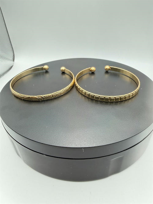 Two gold tone bangle bracelets from Republic Mercantile, showcasing sleek, matching jewelry with polished finishes.