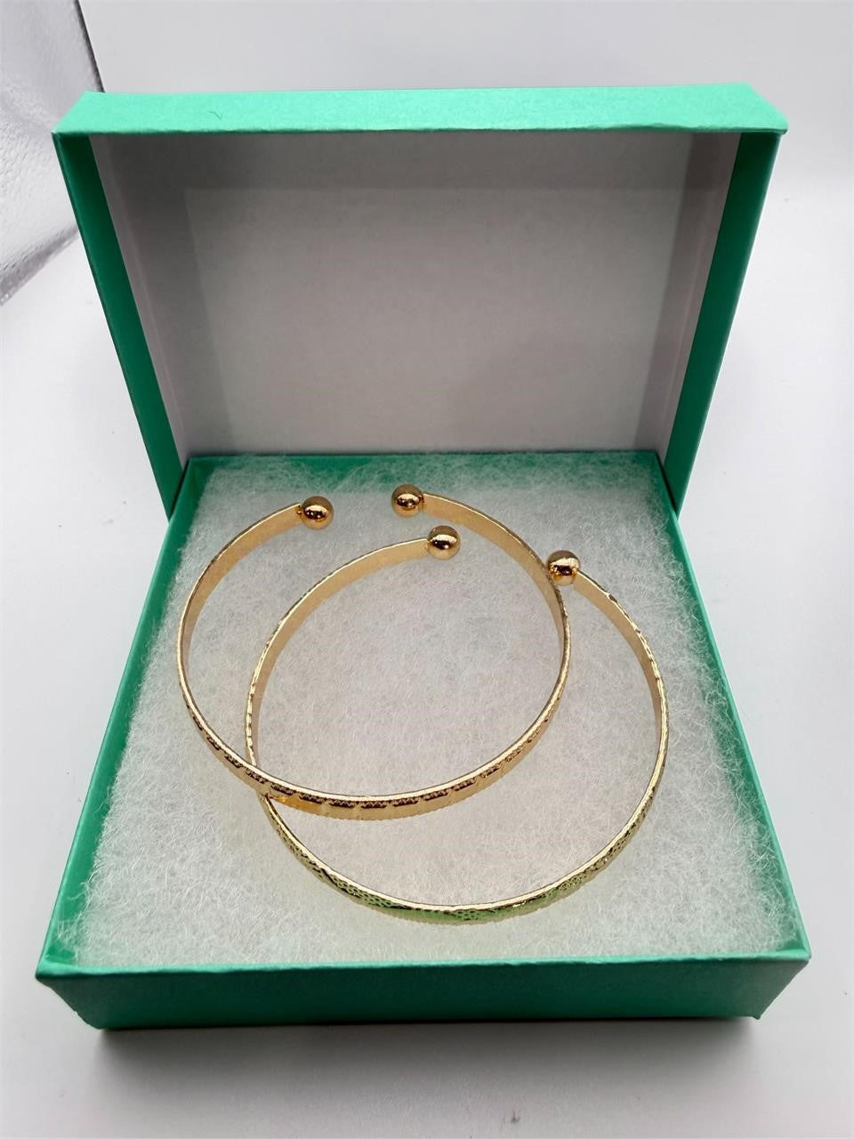 Two gold tone bangle bracelets from Republic Mercantile set, featuring smooth and textured finishes on shiny metal bands.