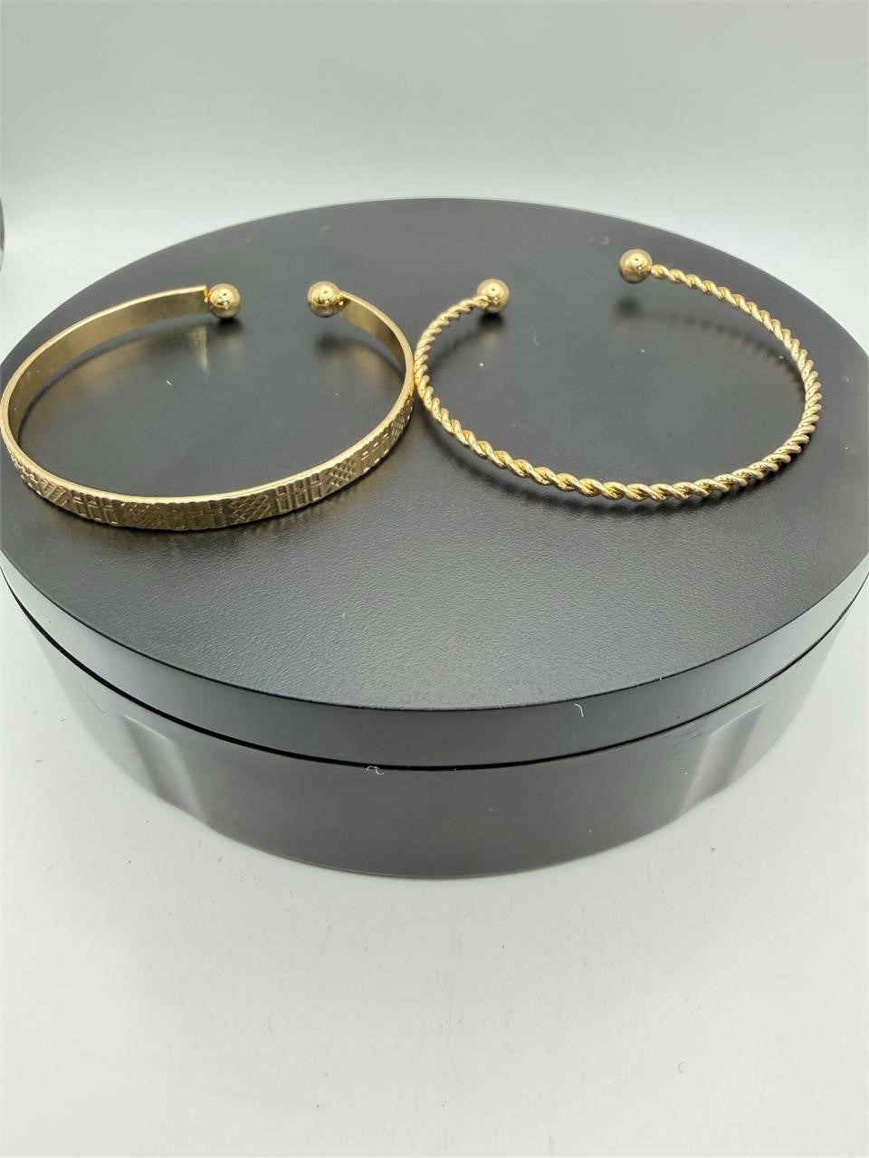 Two gold tone bangle bracelets from the Republic Mercantile 2-piece set, featuring sleek, shiny metal designs.