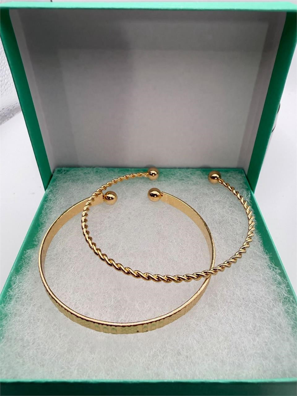 Two gold tone bangle bracelets from Republic Mercantile, stacked and shiny, with smooth and textured surfaces for a stylish look.