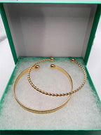 Two gold tone bangle bracelets from Republic Mercantile, stacked and shiny, with smooth and textured surfaces for a stylish look.