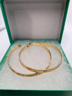 Two gold tone bangle bracelets from Republic Mercantile in a set, featuring sleek, shiny circular designs.