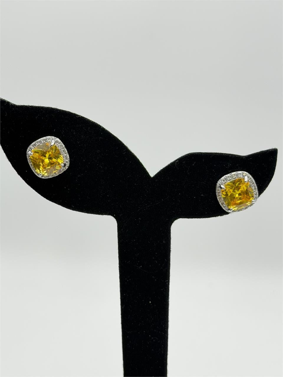 Republic Mercantile yellow crystal stud earrings featuring cushion halo design, sparkling in a jewelry display.