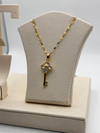 Gold tone crystal key pendant necklace with intricate details, featuring sparkling crystals and a delicate chain.