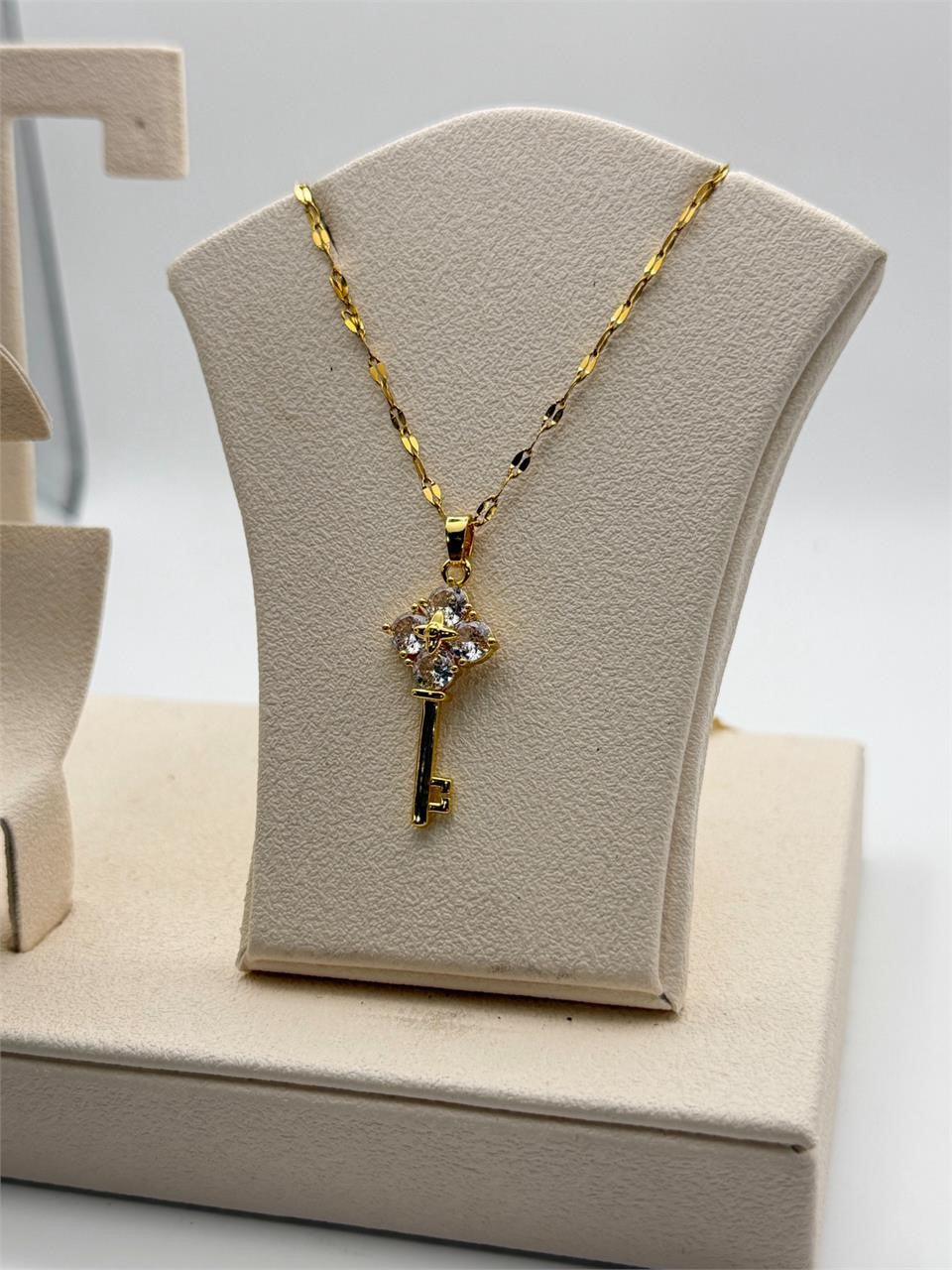 Gold tone crystal key pendant necklace with intricate details, featuring sparkling crystals and a delicate chain.