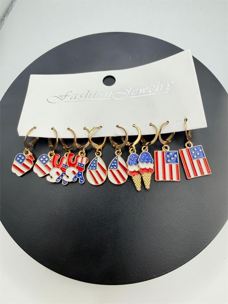 Five pairs of gold-tone USA flag earrings with patriotic stars and stripes, crafted by Republic Mercantile.