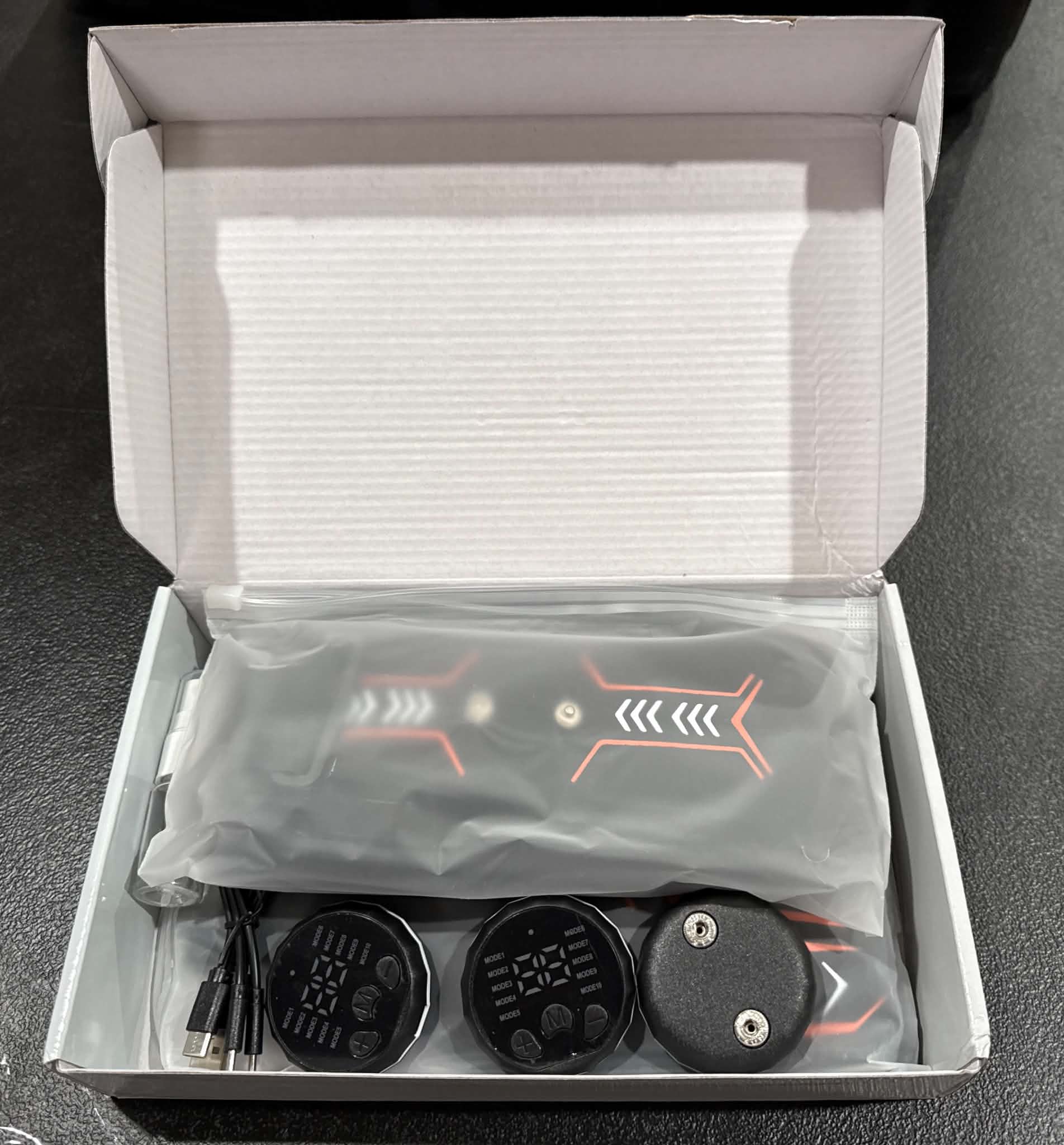 Electric muscle stimulator for fat burning and muscle massage by Republic Mercantile, showing device with electrode pads on skin.