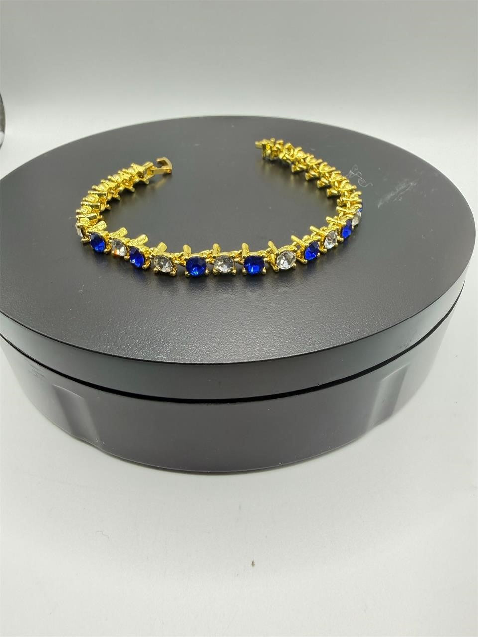 Blue and white gem bracelet set in gold tone with multiple bracelets featuring gemstones and intricate designs, styled together.
