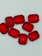 Seven red faceted emerald cut gemstones, 9x10mm, showcasing their vibrant color and sparkling facets, from Republic Mercantile.