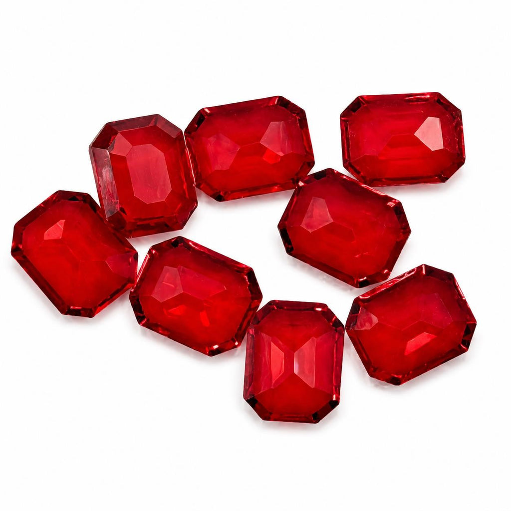 Seven red faceted emerald cut gemstones, 9x10mm, from Republic Mercantile, showcasing their vibrant color and sparkling facets.