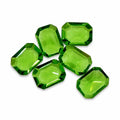 Six green emerald cut gemstones, 5x7mm, from Republic Mercantile, arranged in a row showcasing their vibrant color and clarity.