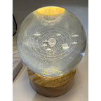 Laser etched crystal ball with LED stand featuring universe design, displayed on a sleek black base.