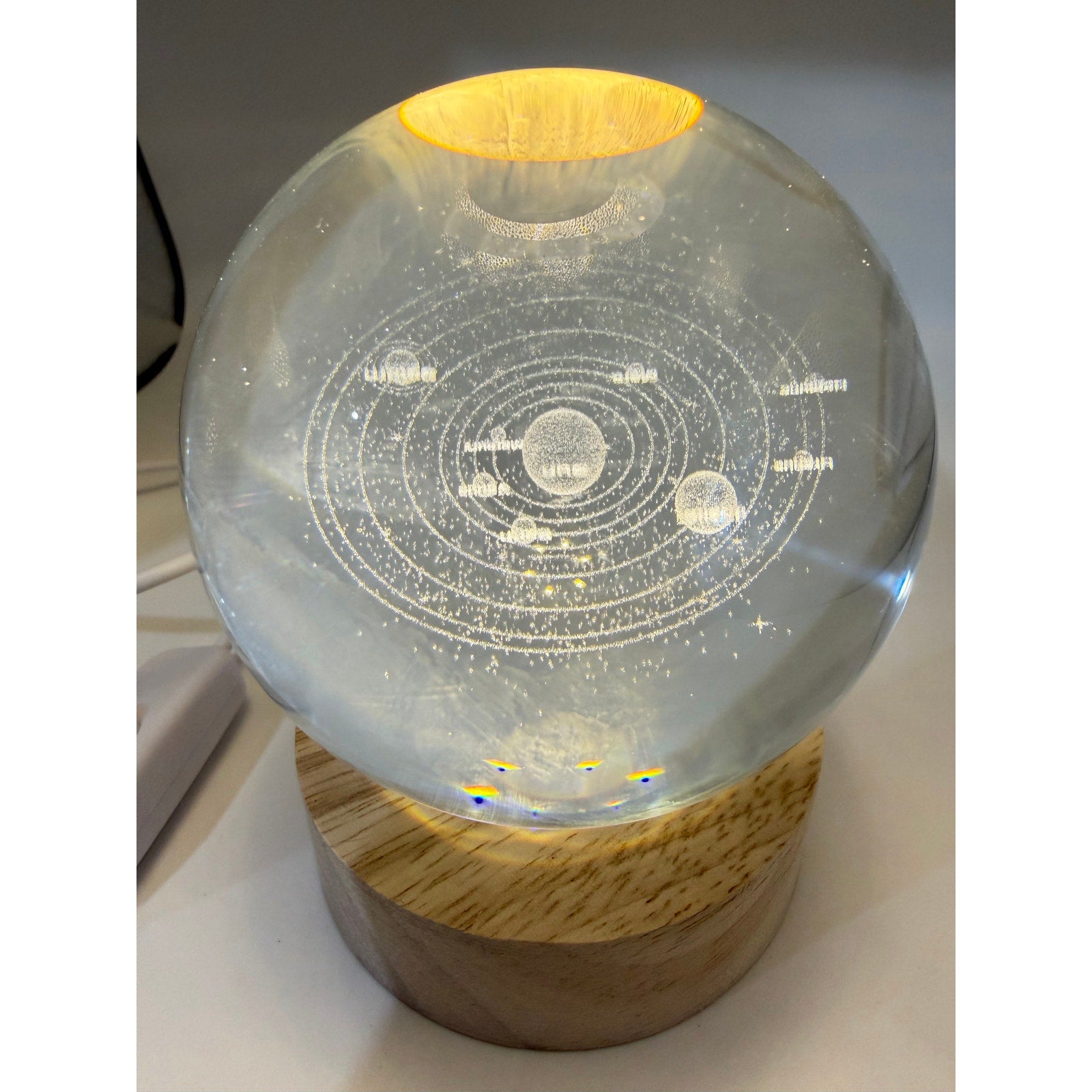Laser etched crystal ball with LED stand featuring universe design, displayed on a sleek black base.