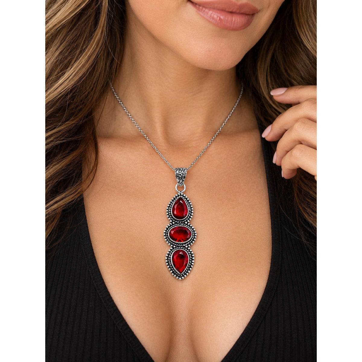 Red garnet gemstone jewelry pendant featuring oval and pear-shaped stones set in sterling silver plating.